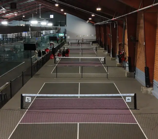 Wide shot of the pickleball courts — show the indoor setup, clean lines, good lighting. 